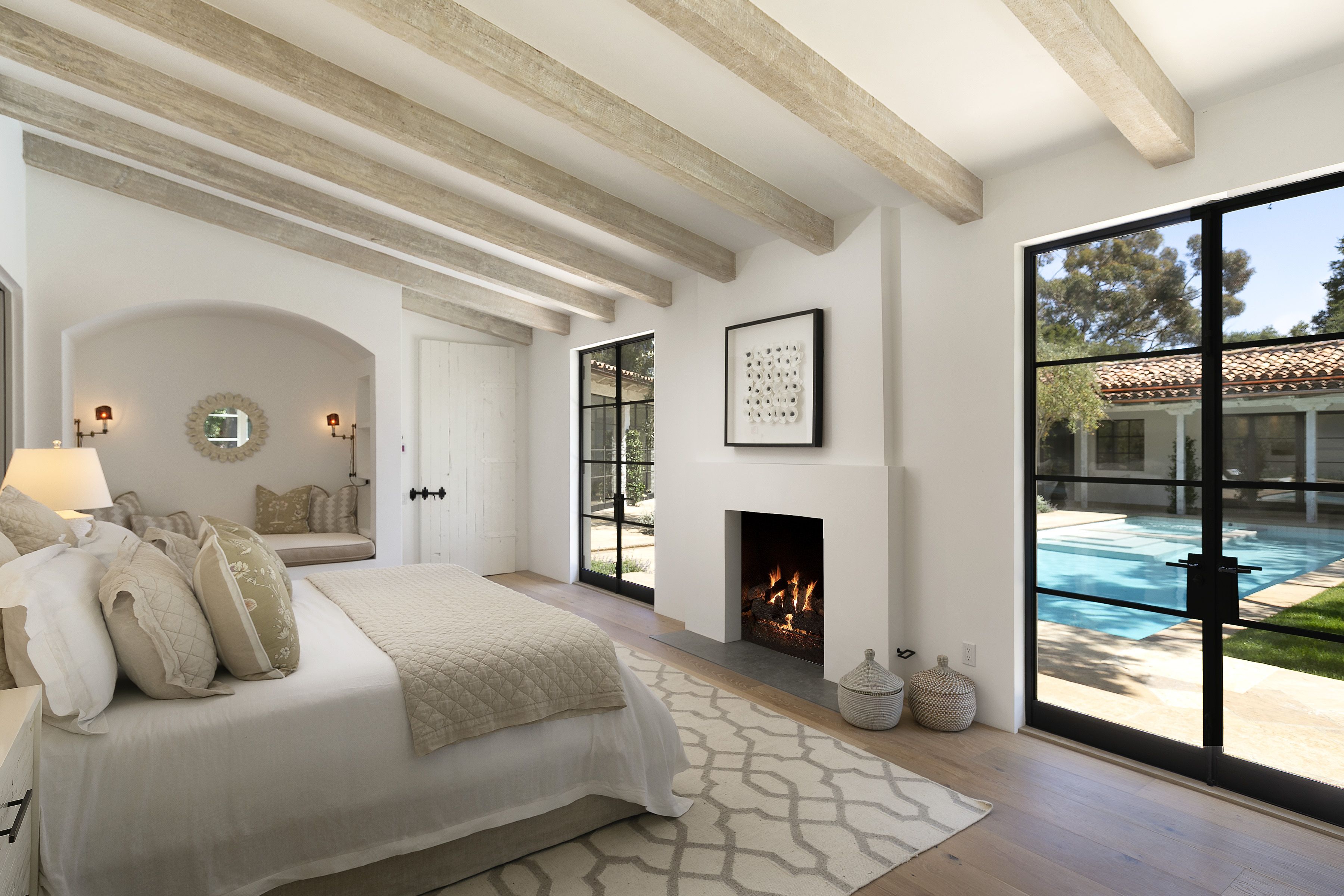bedroom with fireplace and glass doors overlooking pool
